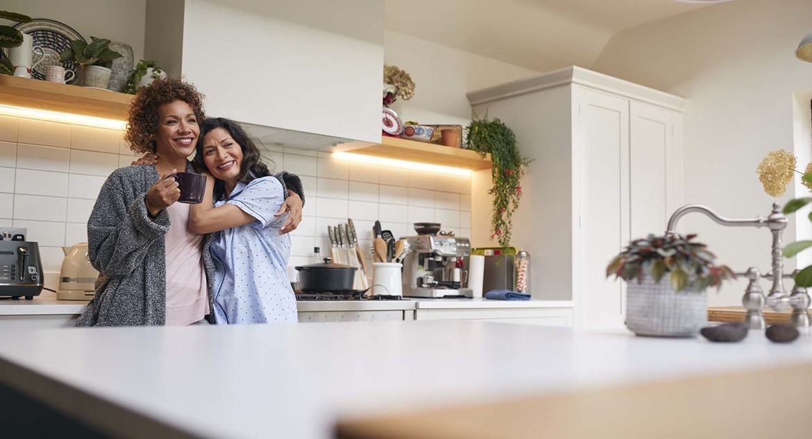 Two woman hugging in their kitchen