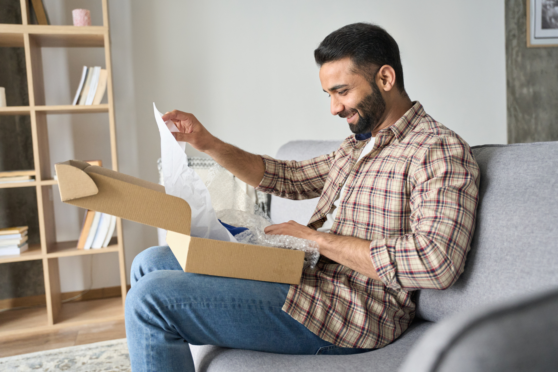 Man in a checked shirt unpackaging a package sent by a retailer