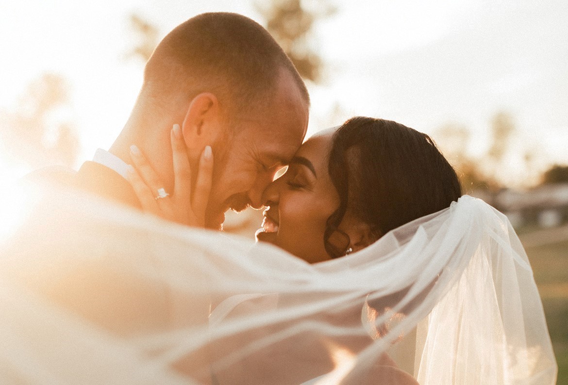 Married couple embracing with veil wrapped around them