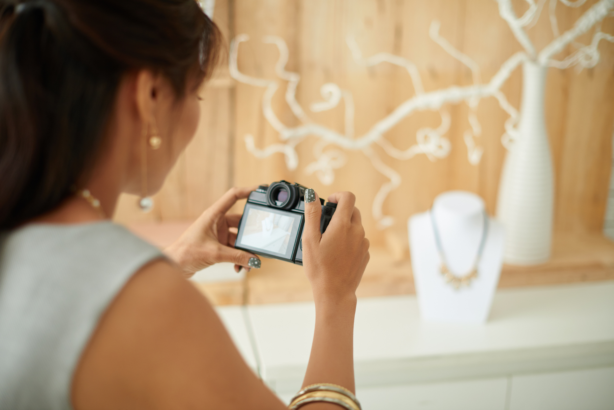 Woman taking a professional photo of jewellery on a display stand