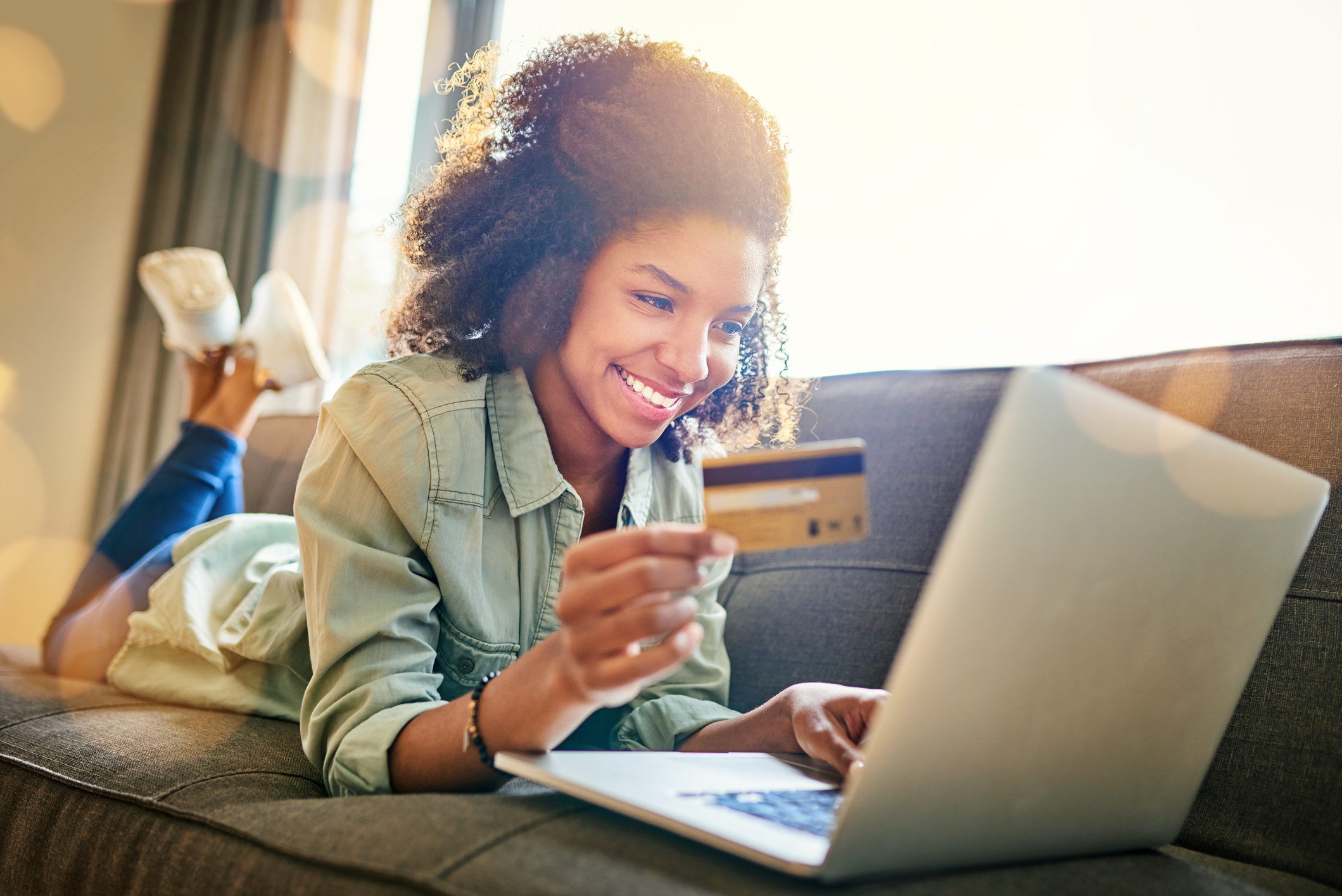 Woman lounging on her sofa shopping online with a credit card