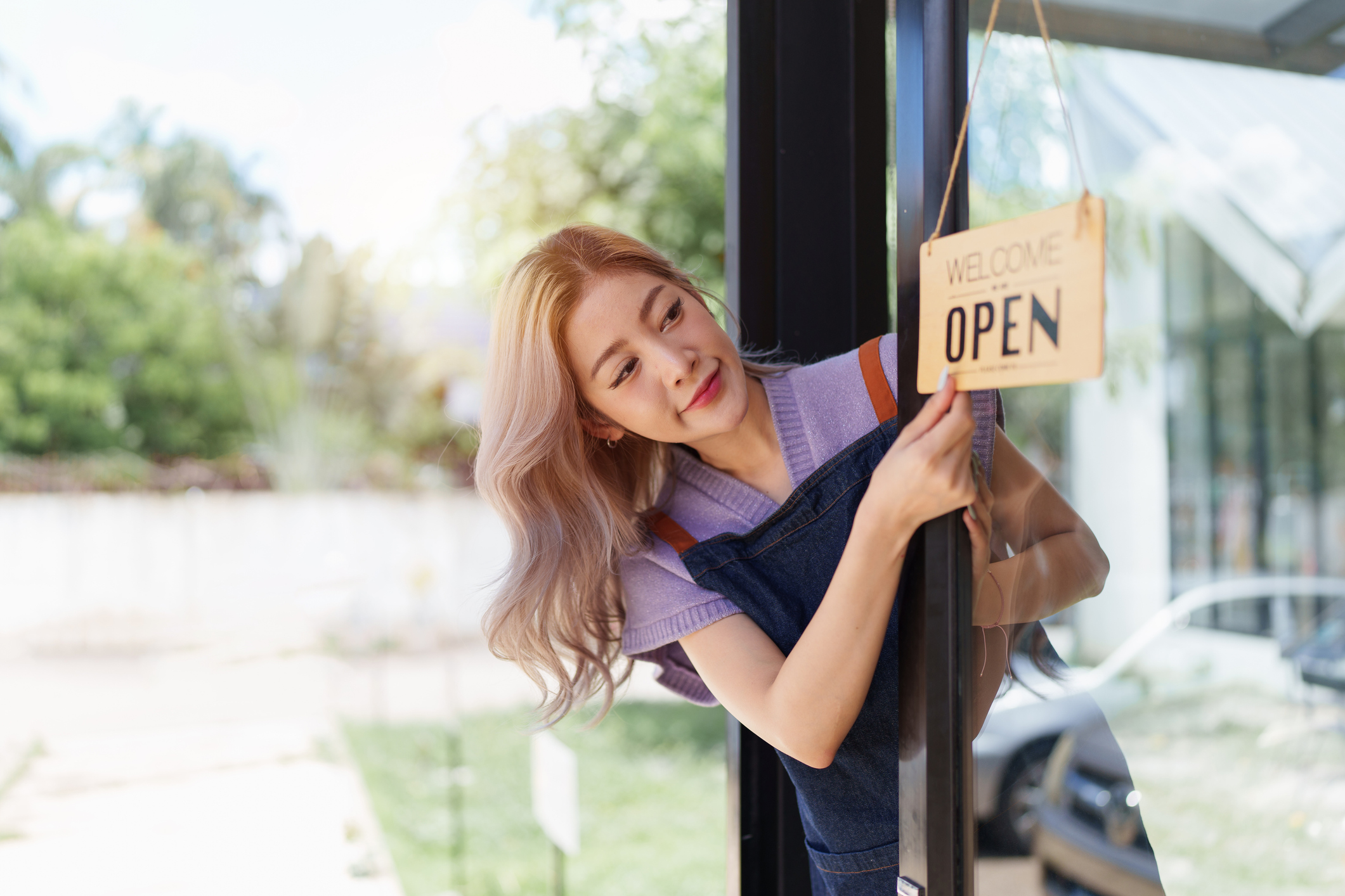 Shop owner turning the sign on her door over to say it is now open